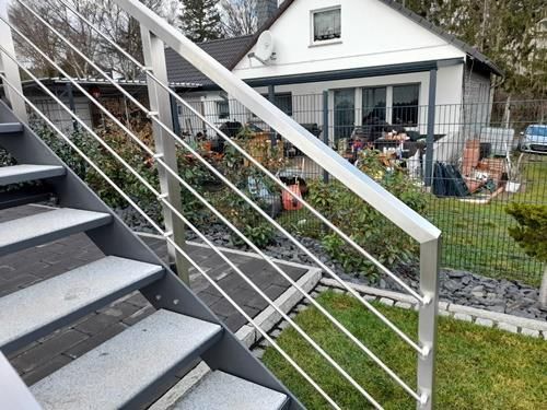 Eine Treppe, die zu einem Haus mit einem Edelstahlgeländer hinaufführt.