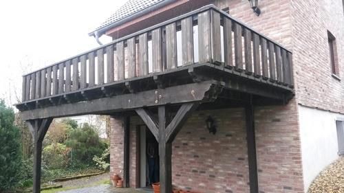 An der Seite eines Backsteingebäudes ist ein Holzbalkon angebracht.