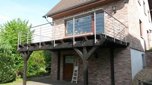 Ein Backsteinhaus mit einem Balkon und einer Leiter davor.