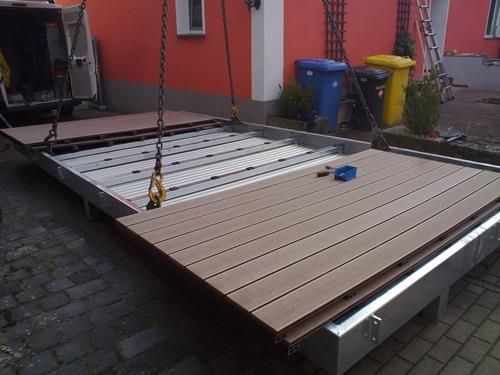 Ein Holzdeck wird von einem Kran angehoben