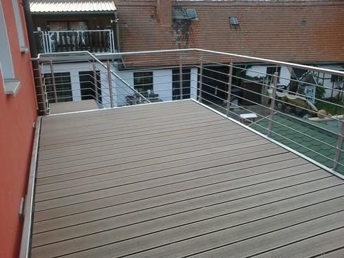 Ein Balkon mit Edelstahlgeländer und Holzterrasse