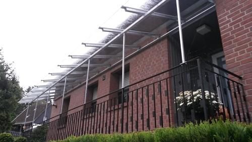 Ein Backsteingebäude mit einem Balkon und einem Vordach darüber.