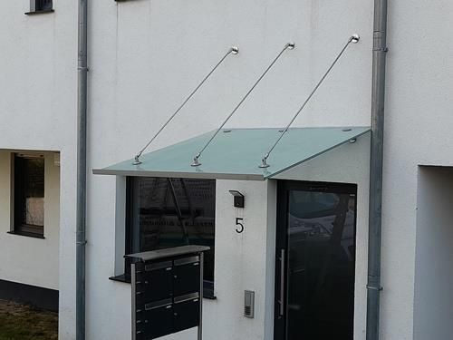 Ein weißes Gebäude mit einem Glasdach über der Tür