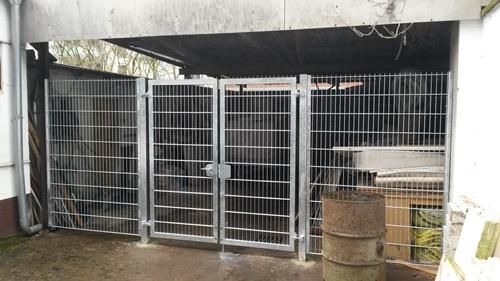 Ein eingezäunter Bereich mit einem Fass davor.