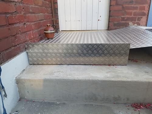 Auf einer Treppe neben einer Tür steht eine Metallkiste.