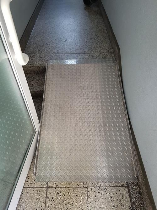 Ein schmaler Flur mit einer Glasrampe, die zu einer Tür führt.