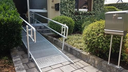 Eine Metallrampe führt zur Eingangstür eines Hauses.