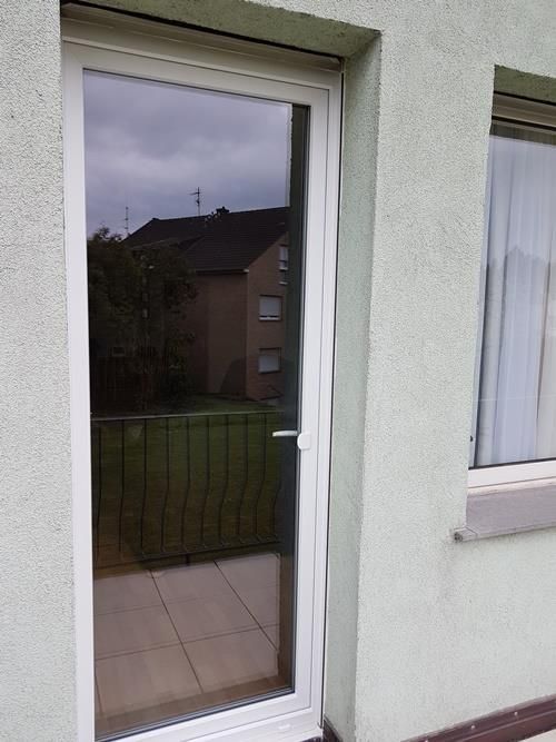 Ein grünes Gebäude mit einer weißen Tür und einem Fenster