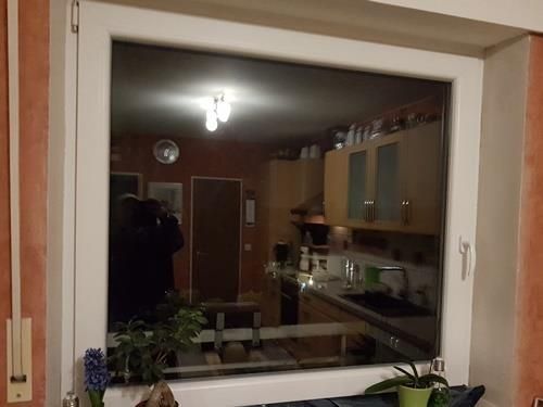 Eine Küche spiegelt sich in einem Wohnzimmerfenster.
