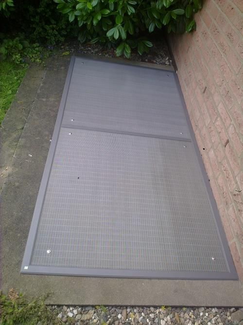 An der Seite eines Backsteingebäudes befindet sich eine Fliegengittertür.