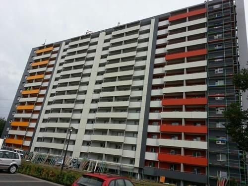 Ein großes Wohnhaus mit einem davor geparkten roten Auto.