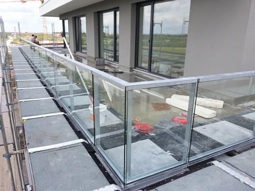 An der Seite eines Gebäudes wird ein Balkon mit Glasgeländer gebaut.