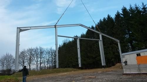 Ein Mann steht vor einer großen Metallkonstruktion, die von einem Kran angehoben wird.