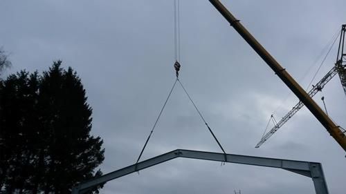 Ein Kran hebt eine Metallkonstruktion in die Luft.