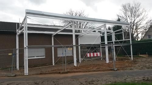 Vor einem braunen Gebäude wird eine Metallkonstruktion errichtet.