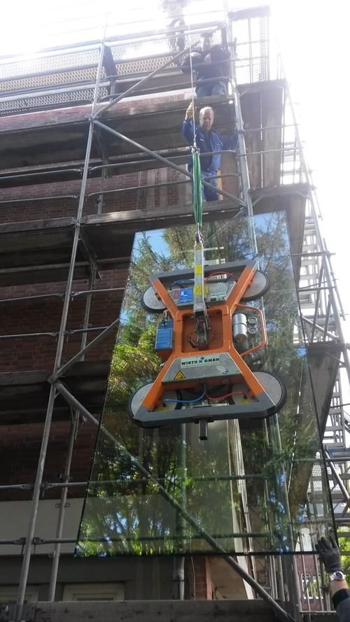 Ein Mann steht auf einem Gerüst und hält einen großen Spiegel.