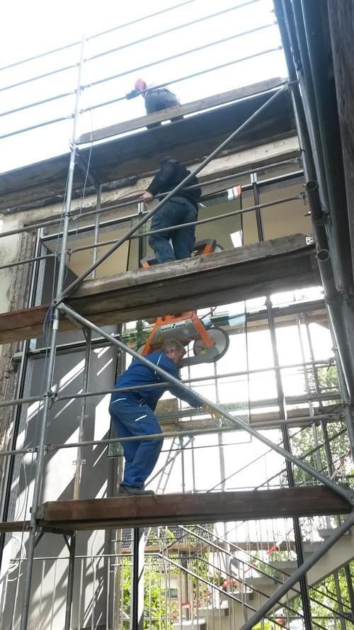 Ein Mann steht auf einem Gerüst und arbeitet an einem Gebäude