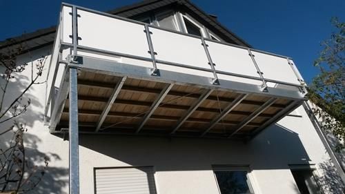 Ein Balkon an der Seite eines Hauses mit einer Holzterrasse.