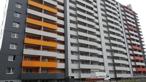 Ein hohes Gebäude mit vielen Balkonen und einem davor geparkten weißen Lieferwagen.