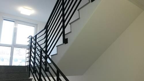 Eine Treppe mit schwarzem Geländer und einem Fenster im Hintergrund.