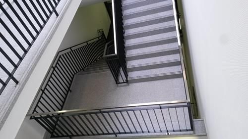 Eine Treppe mit einem Metallgeländer und Stufen in einem Gebäude.