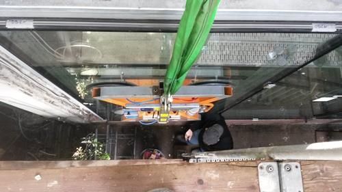 Ein Mann hebt mit einem Kran ein großes Glasfenster an.