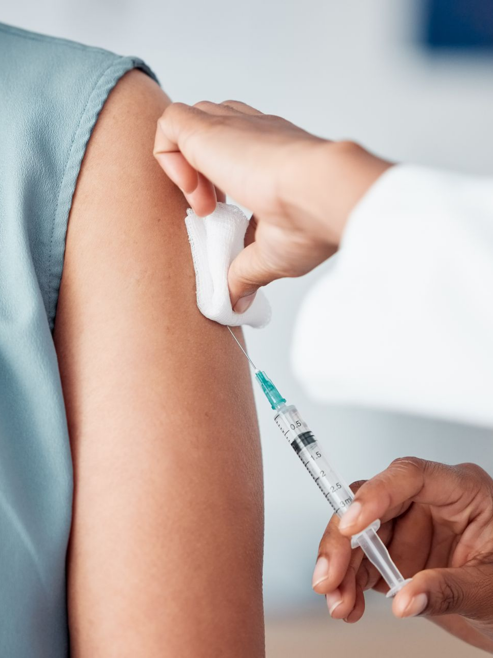 Le médecin administre une injection dans le bras du patient. Un Coton-Tige est présent.