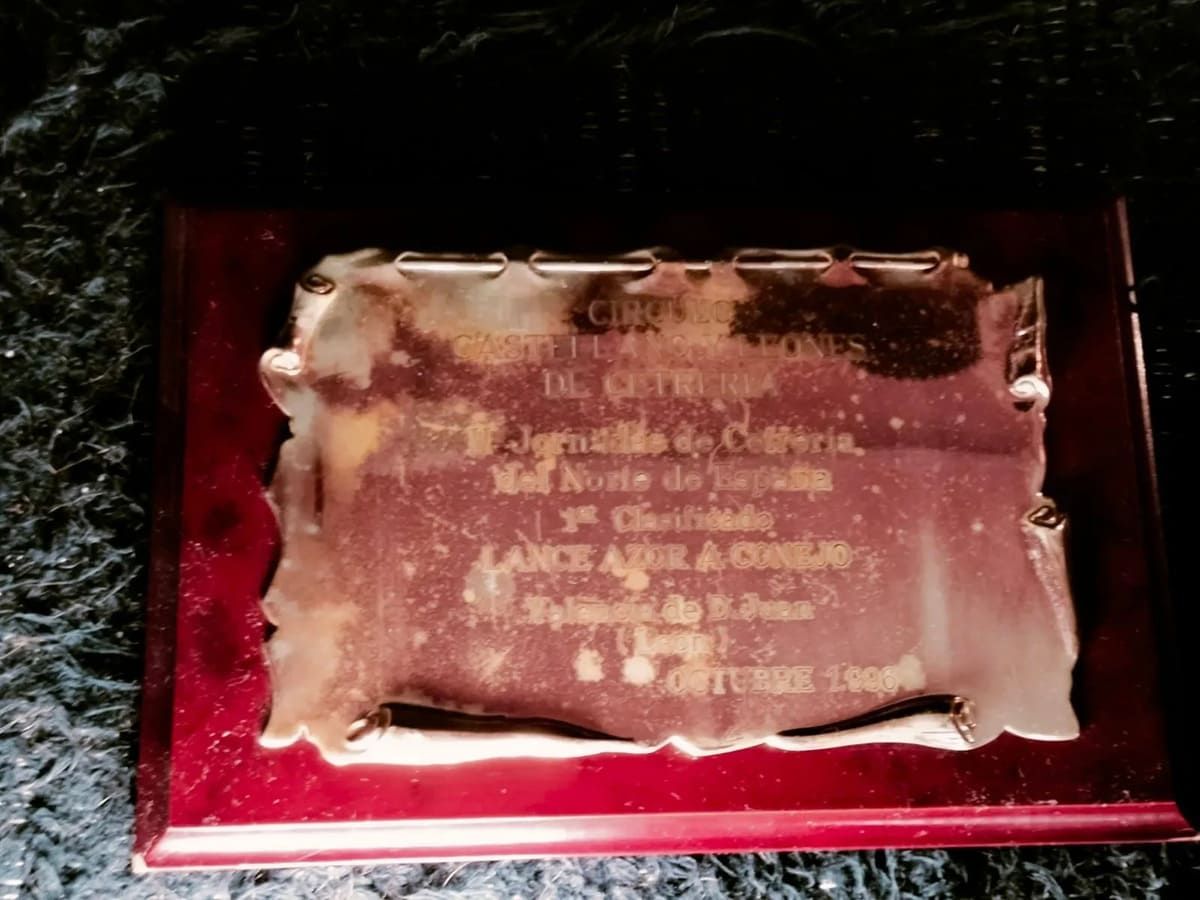 Una placa de metal conmemorativa con texto en español montada sobre una base de madera oscura.