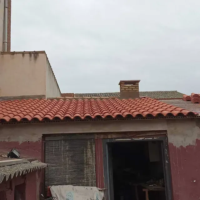 Un edificio con techo de tejas rojas y chimenea.