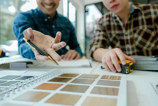 Dos hombres están sentados en una mesa mirando muestras de madera.