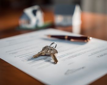 vers la page Vente immobilière. Deux clés posées sur un document légal à côté d'un stylo.