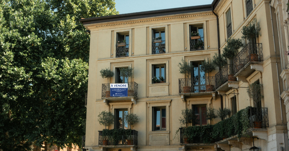 Une pancarte jaune À VENDRE fixée à la rambarde d'un balcon résidentiel.