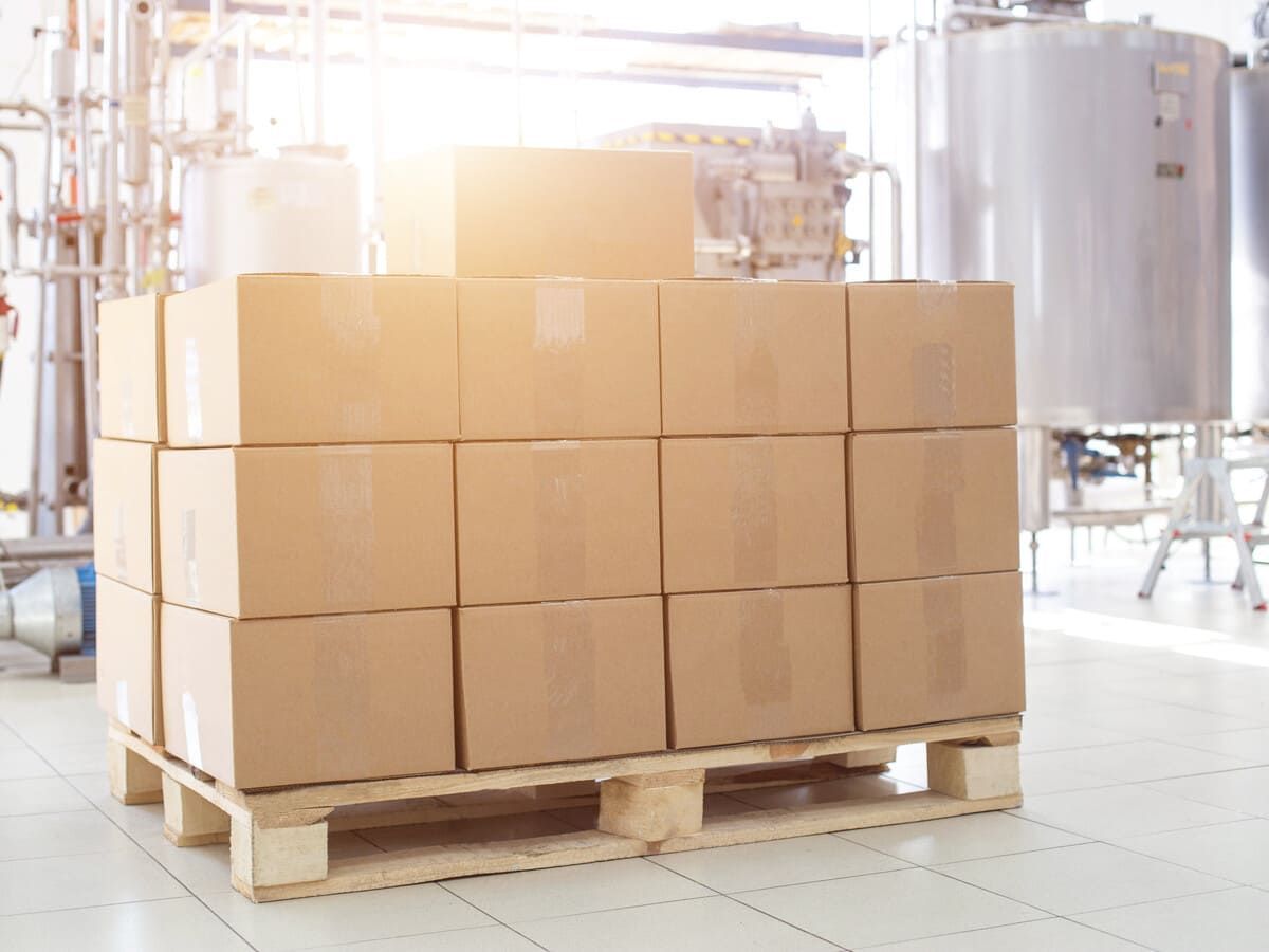 Un palé de madera lleno de cajas de cartón en una fábrica.