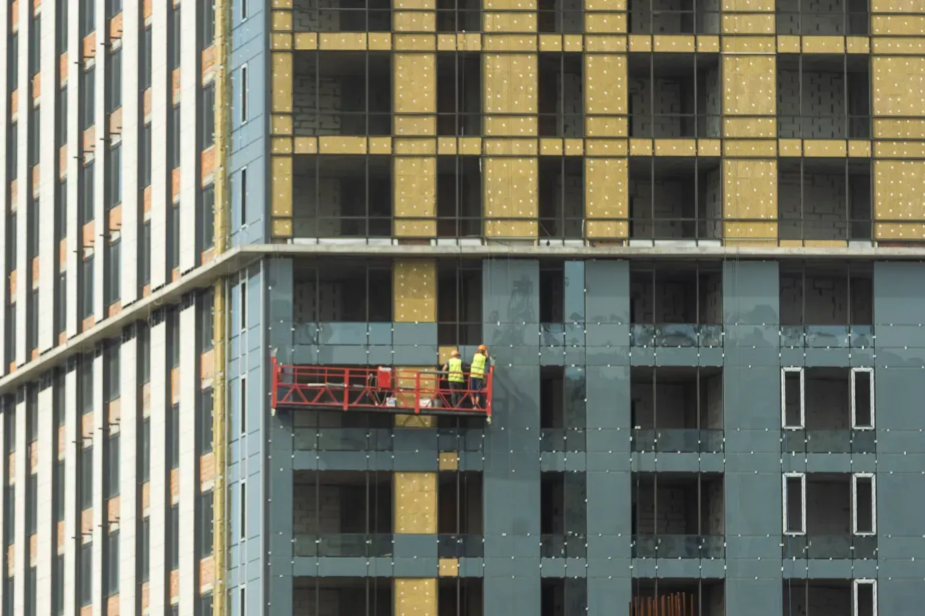 Un grupo de trabajadores de la construcción está trabajando en el lateral de un edificio alto.