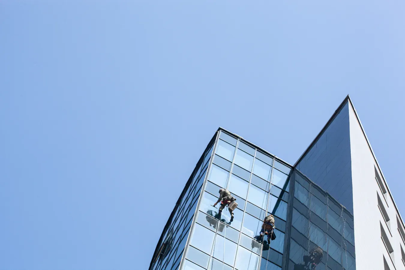 Dos hombres están limpiando las ventanas de un edificio alto.