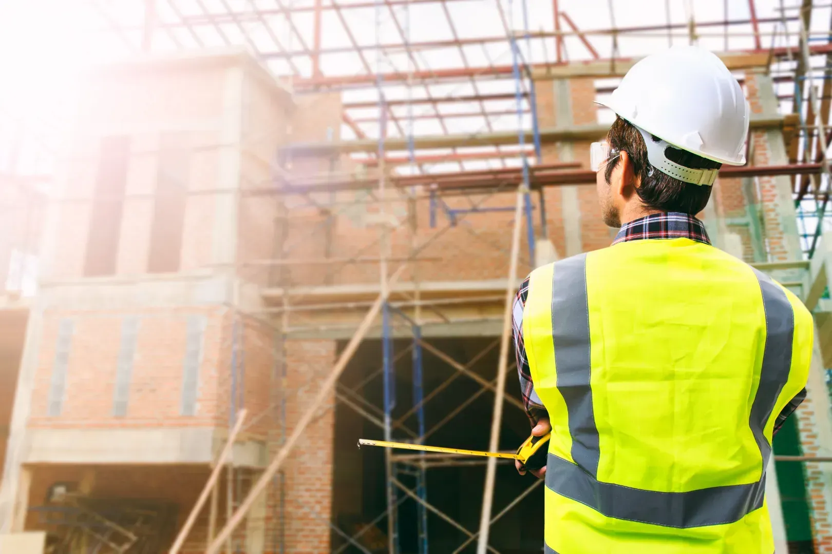 Un trabajador de la construcción está parado frente a un edificio en construcción.