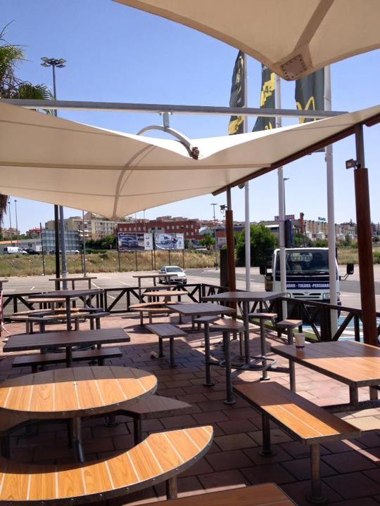 Mesas y bancos bajo sombrillas afuera de un McDonald's