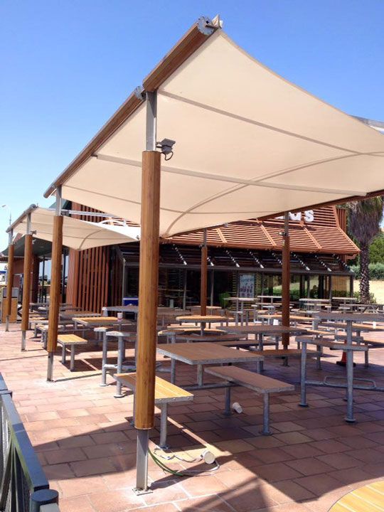 Una fila de mesas de picnic bajo una gran sombrilla