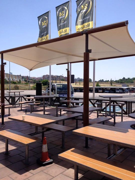 Una fila de mesas de picnic bajo un dosel con banderas que dicen bs