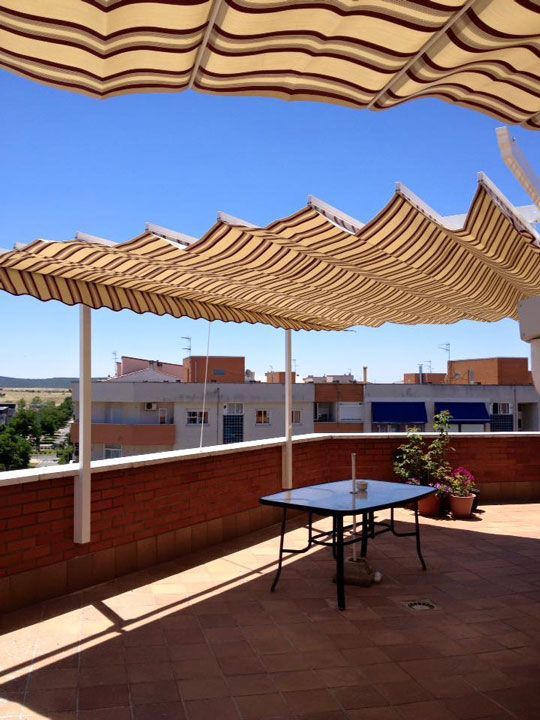 Un patio con una mesa bajo un toldo de rayas