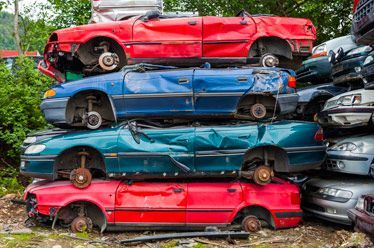 Una pila de coches destrozados apilados uno encima del otro.