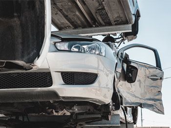 Un automóvil que ha resultado dañado en un accidente se encuentra encima de un camión.