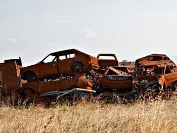 Un montón de coches oxidados están apilados uno encima del otro en un campo.