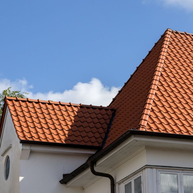 Maison blanche avec un toit de tuiles rouges.