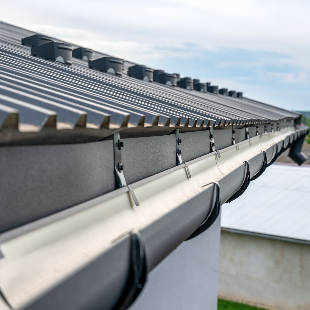 Toiture métallique noire avec gouttières.