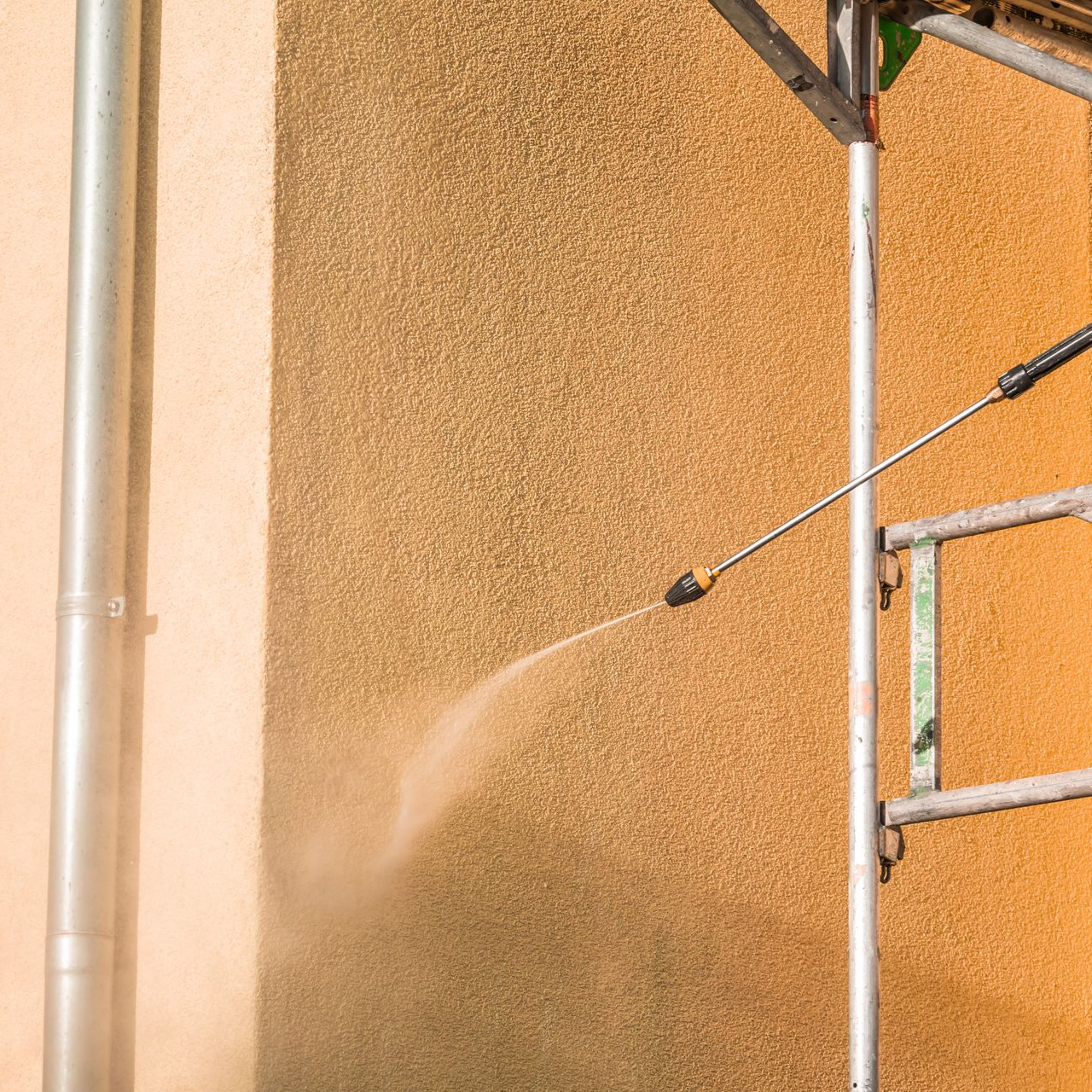 Nettoyage à haute pression d'un mur texturé de couleur marron clair.