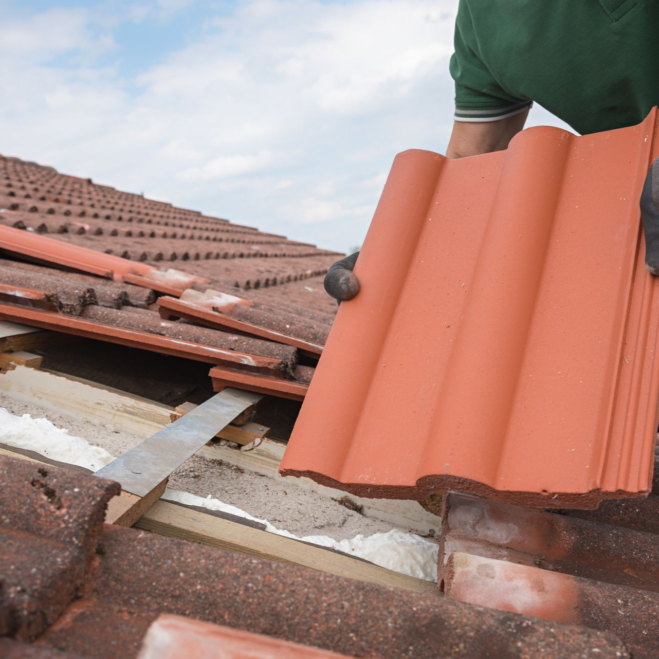Couvreur installant des tuiles en terre cuite.