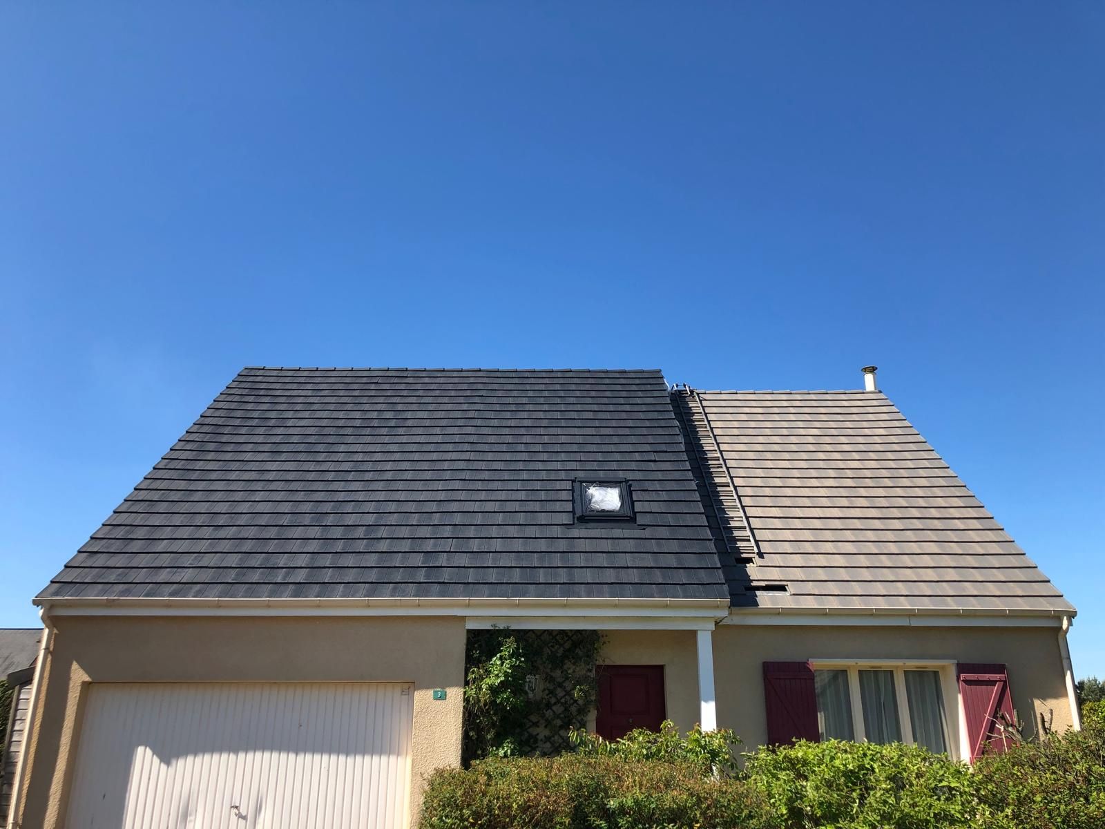 Maison avec un toit à moitié gris et à moitié noir.