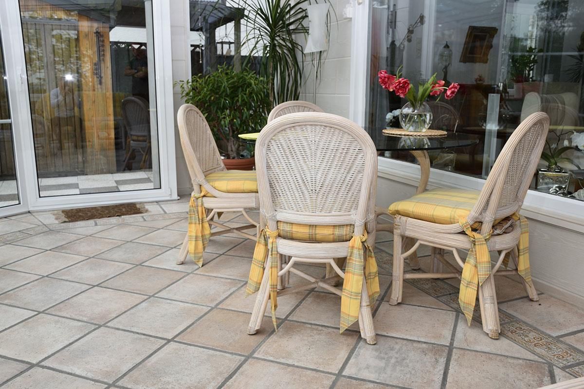 Eine Terrasse mit Korbstühlen und einem Glastisch