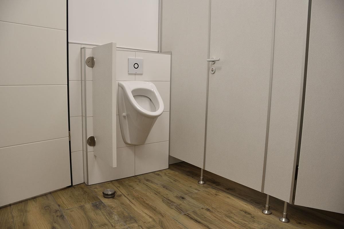 Ein Urinal in einer öffentlichen Toilette mit Holzboden.